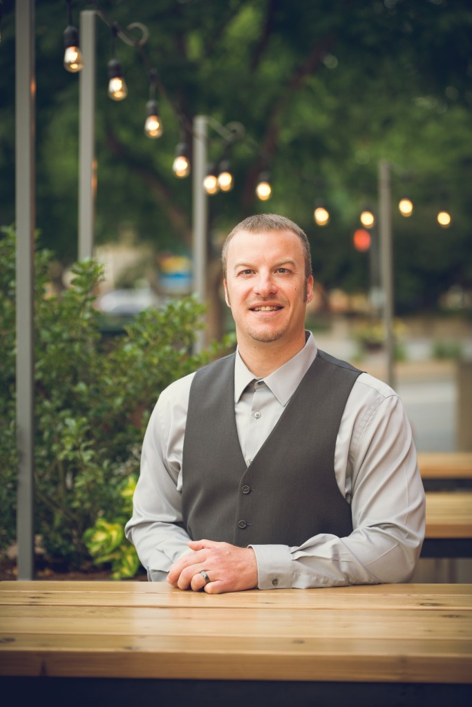 Jason Chadock seated at a table, warm approachable professional portrait